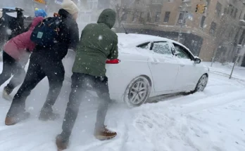 A weather map showing a low-pressure system developing off the East Coast of the United States, indicating potential snow and high winds.