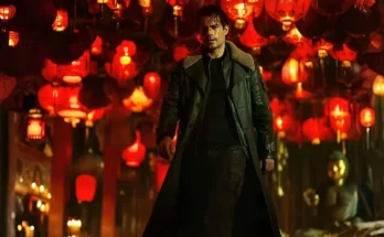 Henry Cavill wearing a trench coat and holding a sheathed katana in a cathedral setting for the Highlander reboot